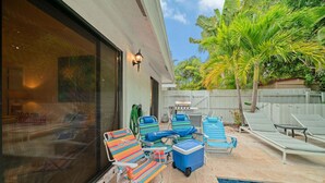 Un pati amb piscina, seients relaxants, una barbacoa i una finestra gran.