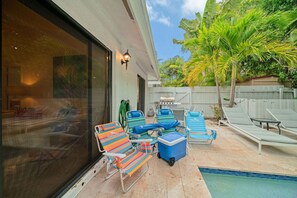 Ein Garten mit Pool, Liegestühlen, Grill und einem großen Fenster.