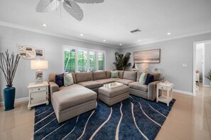 A modern living room with a sectional sofa, a coffee table, and a blue patterned rug. - 1650 Managed by Brampton Park (Pompano Beach)