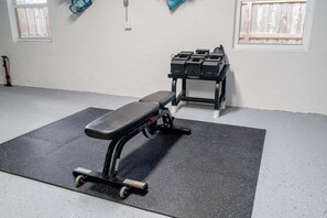 A gym with a bench press, a squat rack, and a small window. - 1650 Managed by Brampton Park (Pompano Beach)