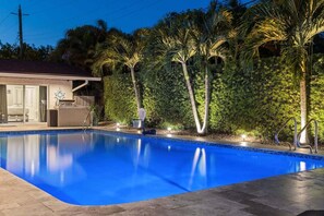 A swimming pool with a clear blue water surface, surrounded by a well-maintained hedge and palm trees. - 1650 Managed by Brampton Park (Pompano Beach)