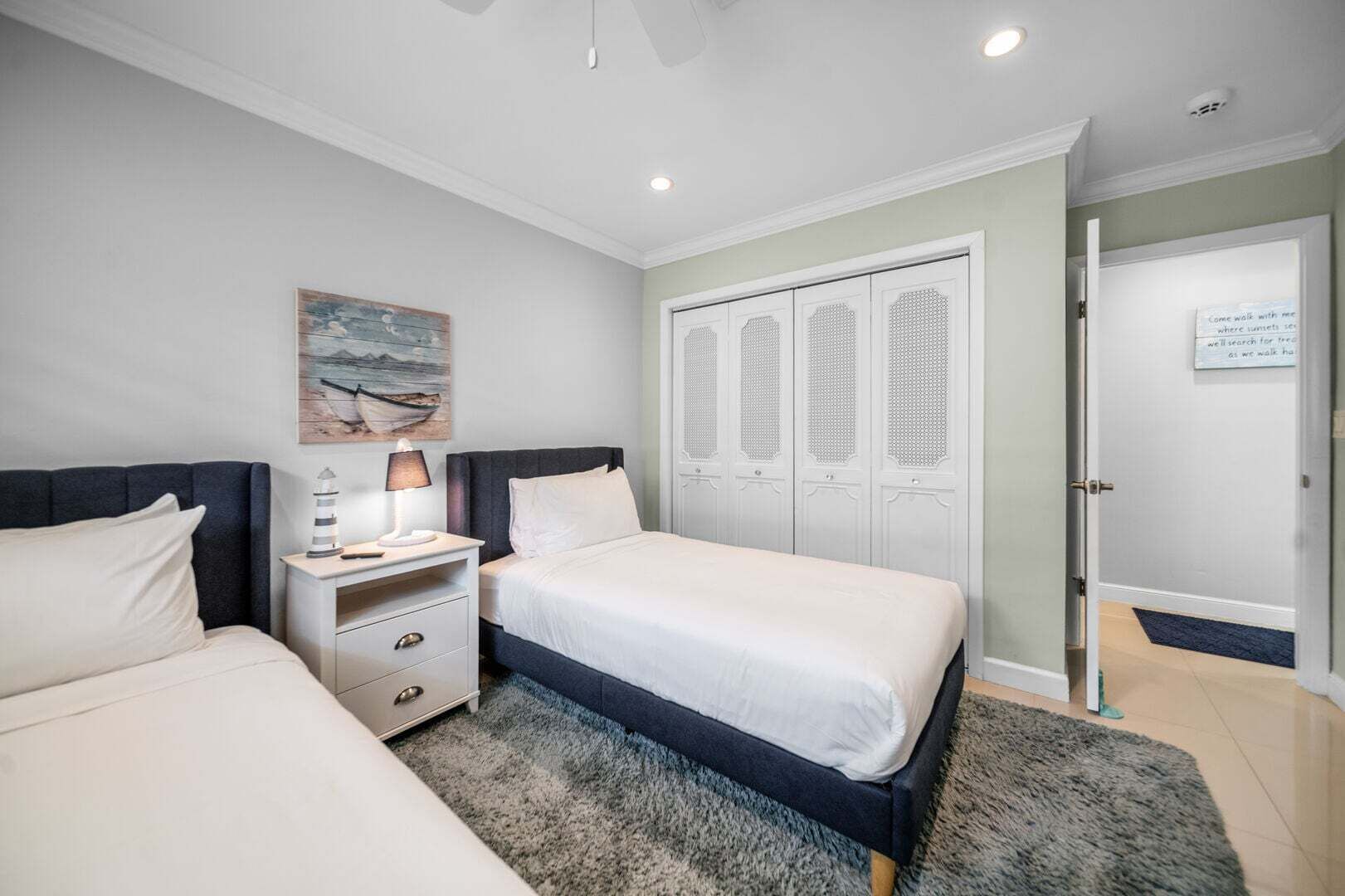A bedroom with a bed, bedside table, lamp, and a wardrobe with a mirror.