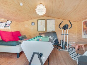 A cozy room with a pool table, exercise equipment, and a sofa.