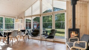 Une pièce spacieuse dotée d’une grande fenêtre, d’une cheminée et d’un coin repas avec des chaises et une table.