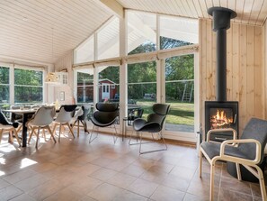 Ein geräumiger Raum mit großem Fenster, Kamin und Essbereich mit Stühlen und Tisch.