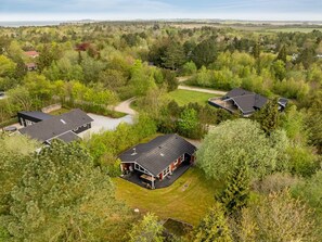 Een woongebied met meerdere huizen, omgeven door weelderige begroeiing en een heldere lucht.