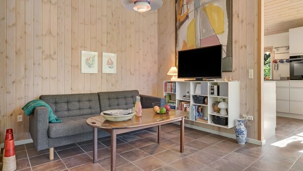 Un salon avec un canapé, une table basse et un téléviseur posé sur un meuble.