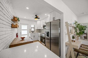 Eine moderne Küche mit weißen Schränken, einem Edelstahl-Kühlschrank und einer Holz-Kochinsel.