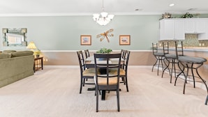 A dining area with a round table and chairs, a chandelier, and framed pictures on the wall. - Golf Villa Near Beach at Myrtlewood | Magnolia Pointe Luster Leaf 4890-304 (Myrtle Beach)
