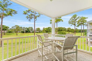 A covered outdoor seating area with a table and chairs, overlooking a well-maintained lawn and trees. - Golf Villa Near Beach at Myrtlewood | Magnolia Pointe Luster Leaf 4890-304 (Myrtle Beach)