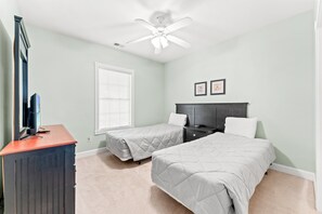 A bedroom with two beds, a desk, a ceiling fan, and two framed pictures on the wall. - Golf Villa Near Beach at Myrtlewood | Magnolia Pointe Luster Leaf 4890-304 (Myrtle Beach)
