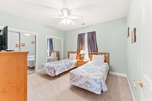 Ein Schlafzimmer mit zwei Betten, einem Deckenventilator, einem Fernseher und einem Kleiderschrank.