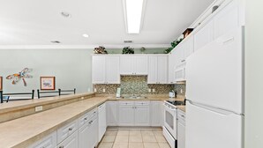 A kitchen with white cabinets, a tiled backsplash, and a stainless steel sink. - Golf Villa Near Beach at Myrtlewood | Magnolia Pointe Luster Leaf 4890-304 (Myrtle Beach)