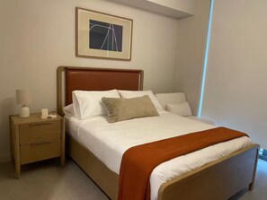 A neatly made bed with a wooden headboard, a bedside table with a lamp, and a framed picture on the wall. - Entire apartment in Miami – NEW (Miami)