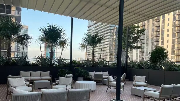 A rooftop terrace with outdoor seating, palm trees, and a view of high-rise buildings. - Entire apartment in Miami – NEW (Miami)