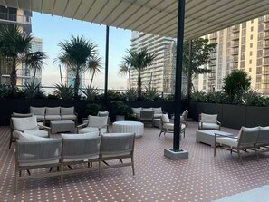 A rooftop terrace with outdoor seating, palm trees, and a view of high-rise buildings. - Entire apartment in Miami – NEW (Miami)