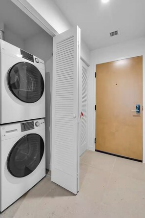 A laundry room with stacked washing machines and a closed door. - Entire apartment in Miami – NEW (Miami)