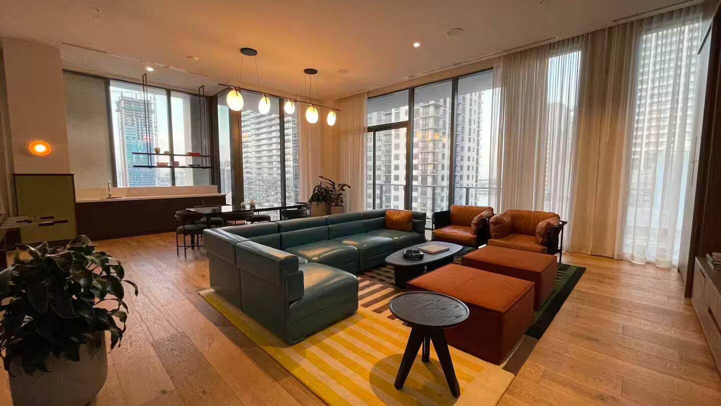 A modern living room with a sectional sofa, a coffee table, and a dining area.