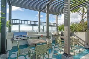 Un espace extérieur abrité, équipé d’un barbecue, de sièges et offrant une vue sur la ville.