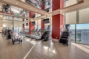 Ein Fitnessstudio mit Laufbändern, Kraftgeräten und Blick auf die Stadt.
