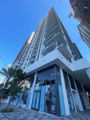 Un immeuble moderne de grande hauteur, doté d’une façade en verre, de grandes fenêtres et d’une entrée imposante avec une enseigne.