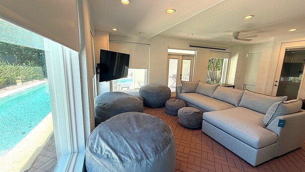 A modern living room with a pool view, a flat-screen TV, and a sectional sofa. - Sea Attached: Private Pool (South Padre Island)