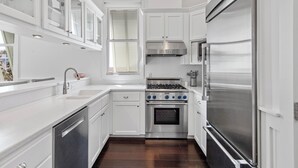 A modern kitchen with white cabinetry, a stainless steel stove, and a large refrigerator. - Sea Attached: Private Pool (South Padre Island)