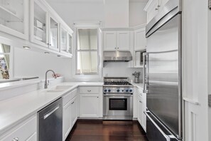 A modern kitchen with white cabinetry, a stainless steel stove, and a large refrigerator. - Sea Attached: Private Pool (South Padre Island)