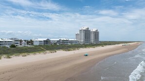 A beachfront hotel with multiple buildings, a sandy beach, and ocean waves. - Sea Attached: Private Pool (South Padre Island)