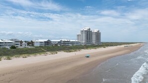 A beachfront hotel with multiple buildings, a sandy beach, and ocean waves. - Sea Attached: Private Pool (South Padre Island)