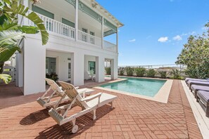 A pool area with lounge chairs and a building with a balcony. - Sea Attached: Private Pool (South Padre Island)