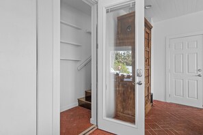 A white door with a glass panel, a wooden cabinet, and a brick floor. - Sea Attached: Private Pool (South Padre Island)