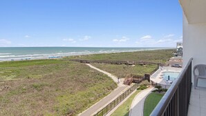 A balcony with a view of the beach, a wooden boardwalk, and a pool area. - Beachfront 3BR/3BA condo with Gulf views in South Padre Island. (South Padre Island)