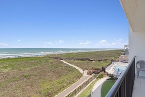 Ein Balkon mit Blick auf den Strand, eine Holzpromenade und ein Poolbereich.