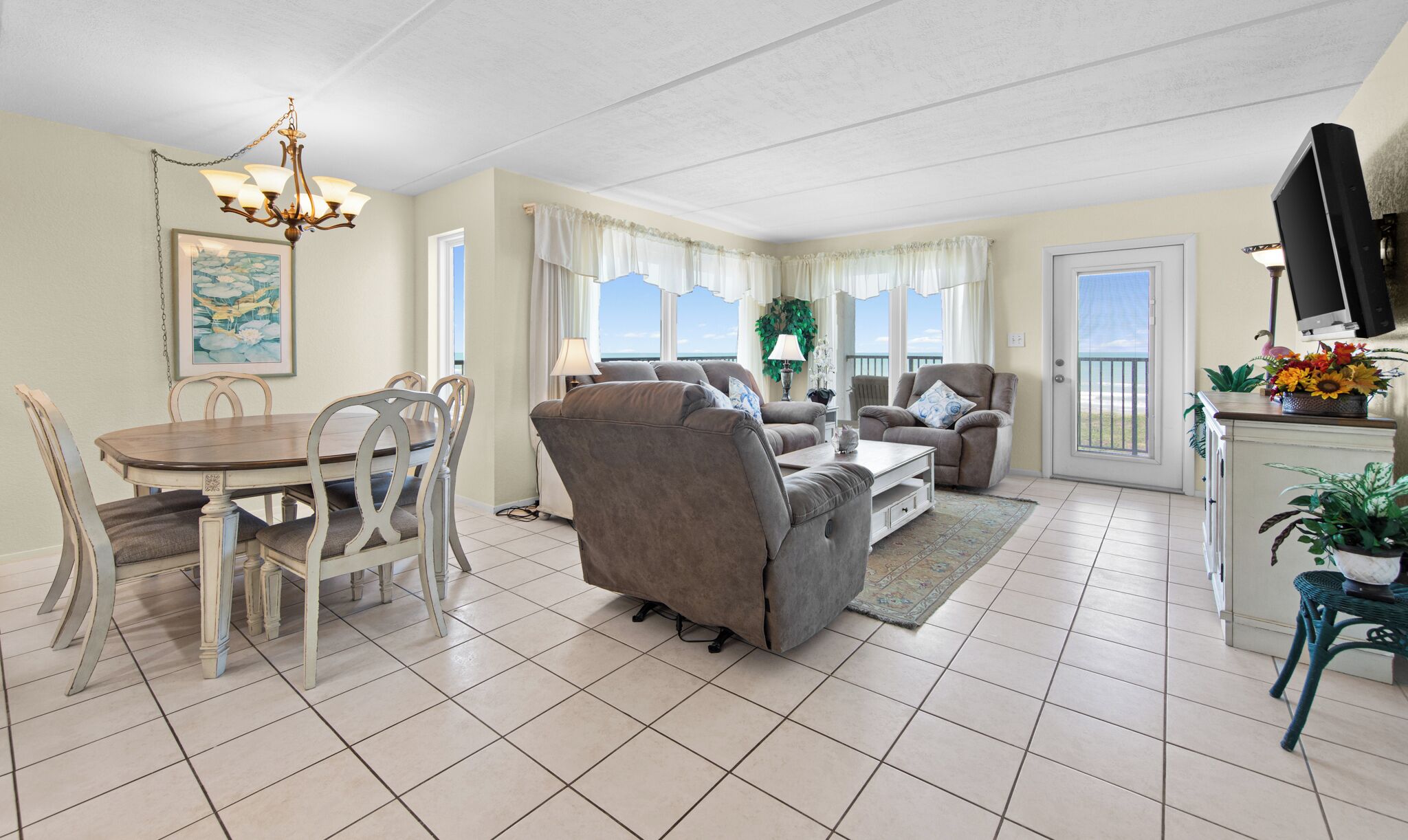A living room with a dining area, a sofa, a TV, and a balcony with a view.