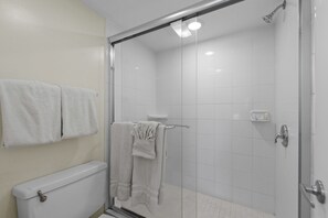 Ein Badezimmer mit einer Duschkabine, einer Toilette und zwei Handtüchern, die an der Wand hängen.