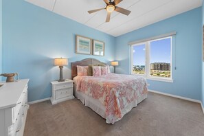 A bedroom with a bed, nightstands, a dresser, a ceiling fan, and a large window with a view. - 3BR, 4BA Gulf-view condo in South Padre Island. (South Padre Island)