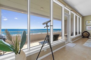 A balcony with a camera on a tripod, large windows, and a view of the ocean. - 3BR, 4BA Gulf-view condo in South Padre Island. (South Padre Island)