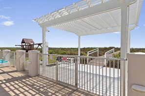 A covered outdoor area with a white gate, a wooden play structure, and a view of the beach. - 3BR, 4BA Gulf-view condo in South Padre Island. (South Padre Island)