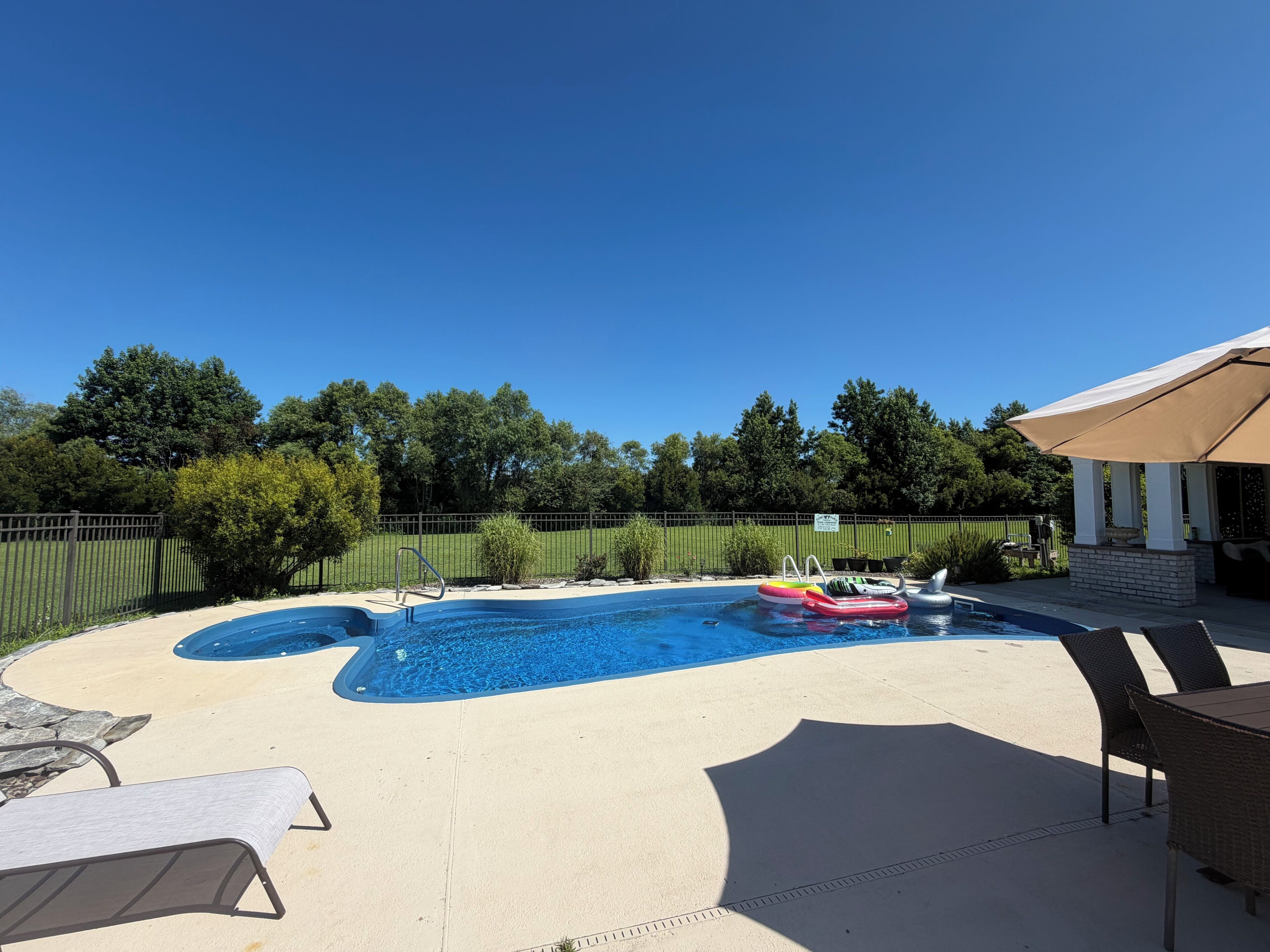 Une piscine avec un plongeoir, des chaises longues et un parasol.