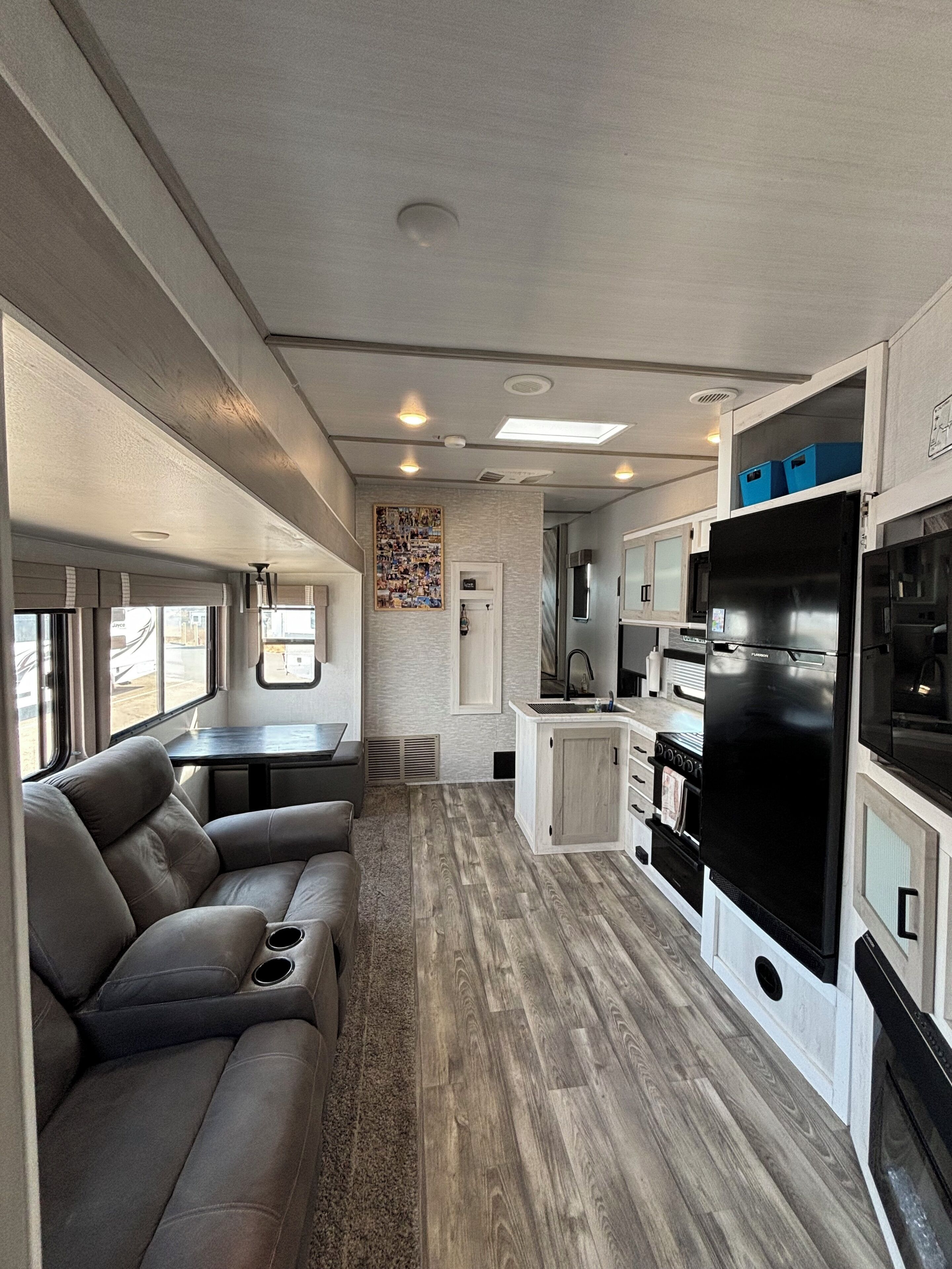 A compact kitchen with a refrigerator, stove, and sink. There is a seating area with a sofa and a table.