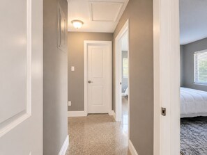 A hallway with a door leading to a bedroom, carpeted floor, and a ceiling light fixture.