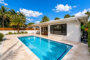 Une maison moderne dotée d’une piscine, de mobilier de jardin et de palmiers.