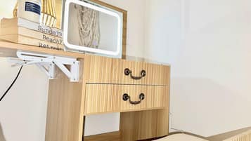 Une table de chevet en bois, avec une lampe blanche, un miroir et une bougie.