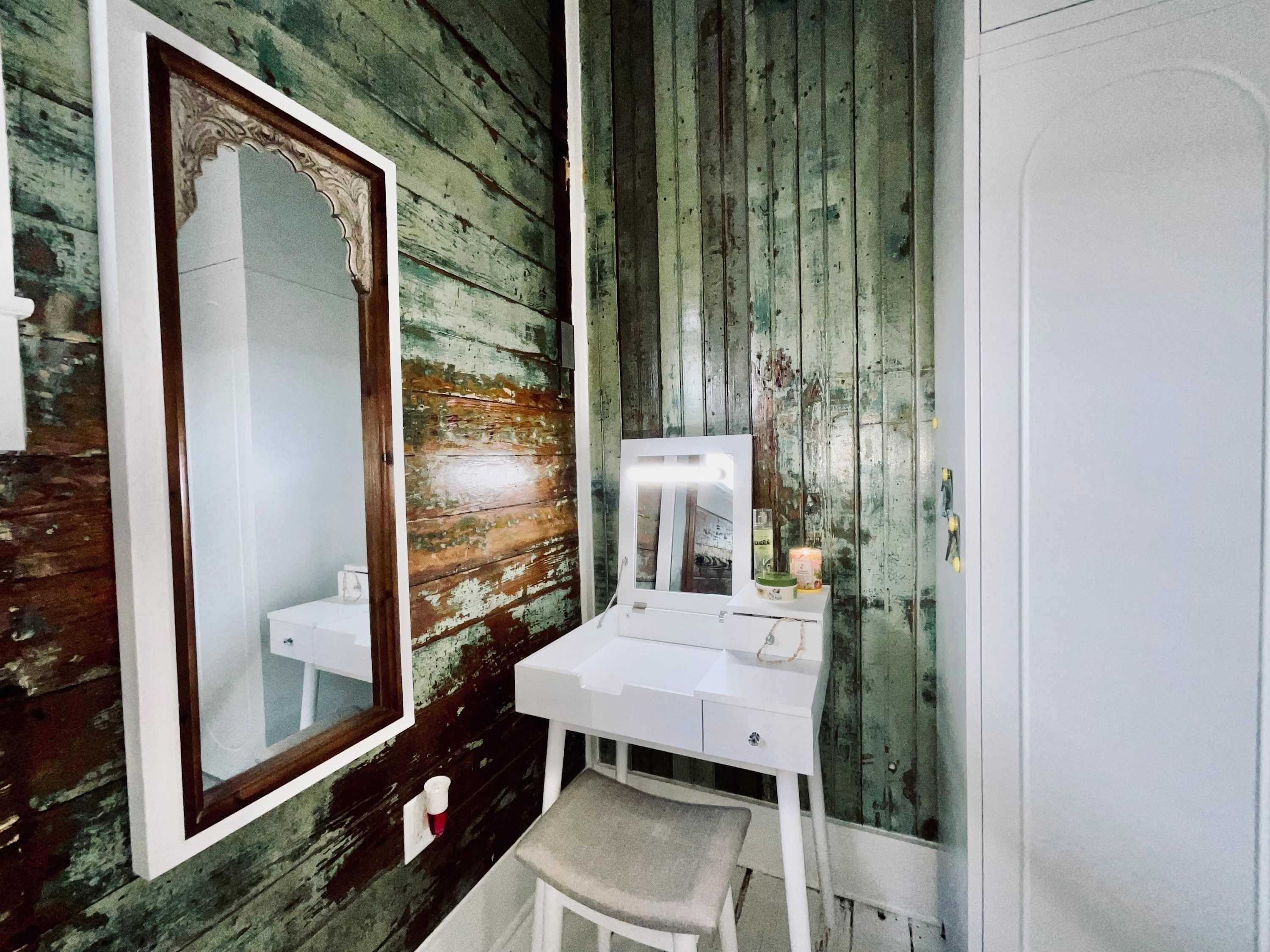 Ein Badezimmer mit Holzwand, einem weißen Waschtisch, einem Spiegel und einem Waschbecken.