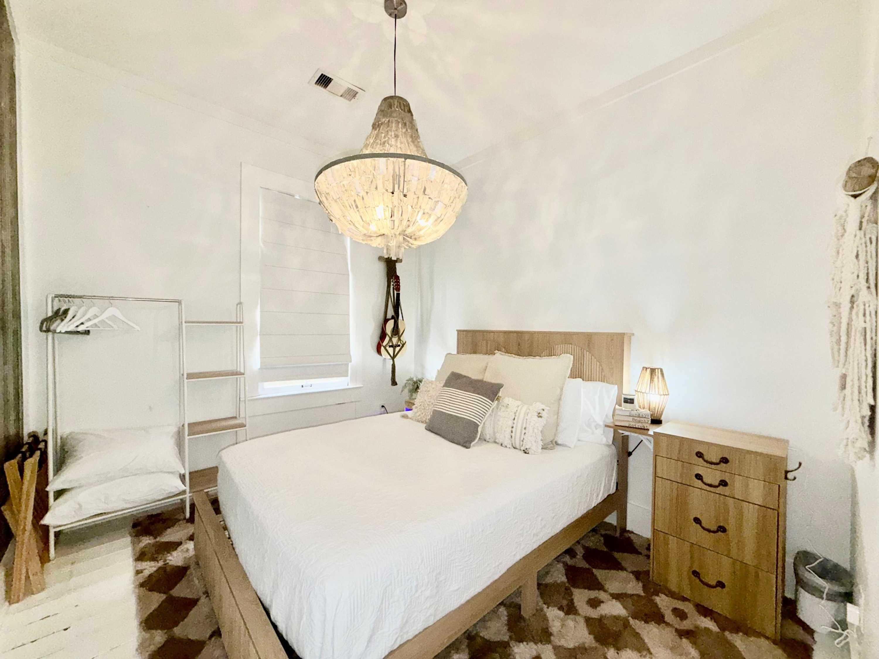 A bedroom with a bed, bedside table, lamp, and a hanging light fixture.