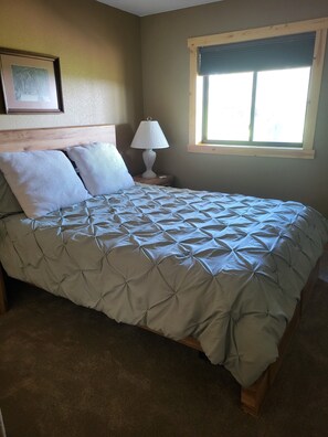 A bedroom with a bed, a nightstand, a lamp, a window, and a picture on the wall. - Shell Lake Getaway. Spacious 3-bedroom barndominium in nearby Beaver Brook (Shell Lake)