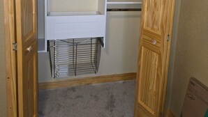 Ein begehbarer Kleiderschrank mit Holztüren, einem Metallgestell und einer weißen Regaleinheit.