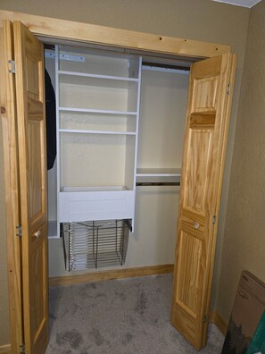 A walk-in closet with wooden doors, a metal rack, and a white shelving unit. - Shell Lake Getaway. Spacious 3-bedroom barndominium in nearby Beaver Brook (Shell Lake)