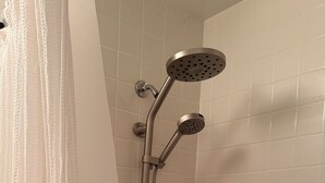 A shower with a handheld showerhead and a handheld rain showerhead, a curtain, and a bathtub. - Cozy 1-bedroom condo 4miles from uc Berkeley with lots of public transportation (Emeryville)